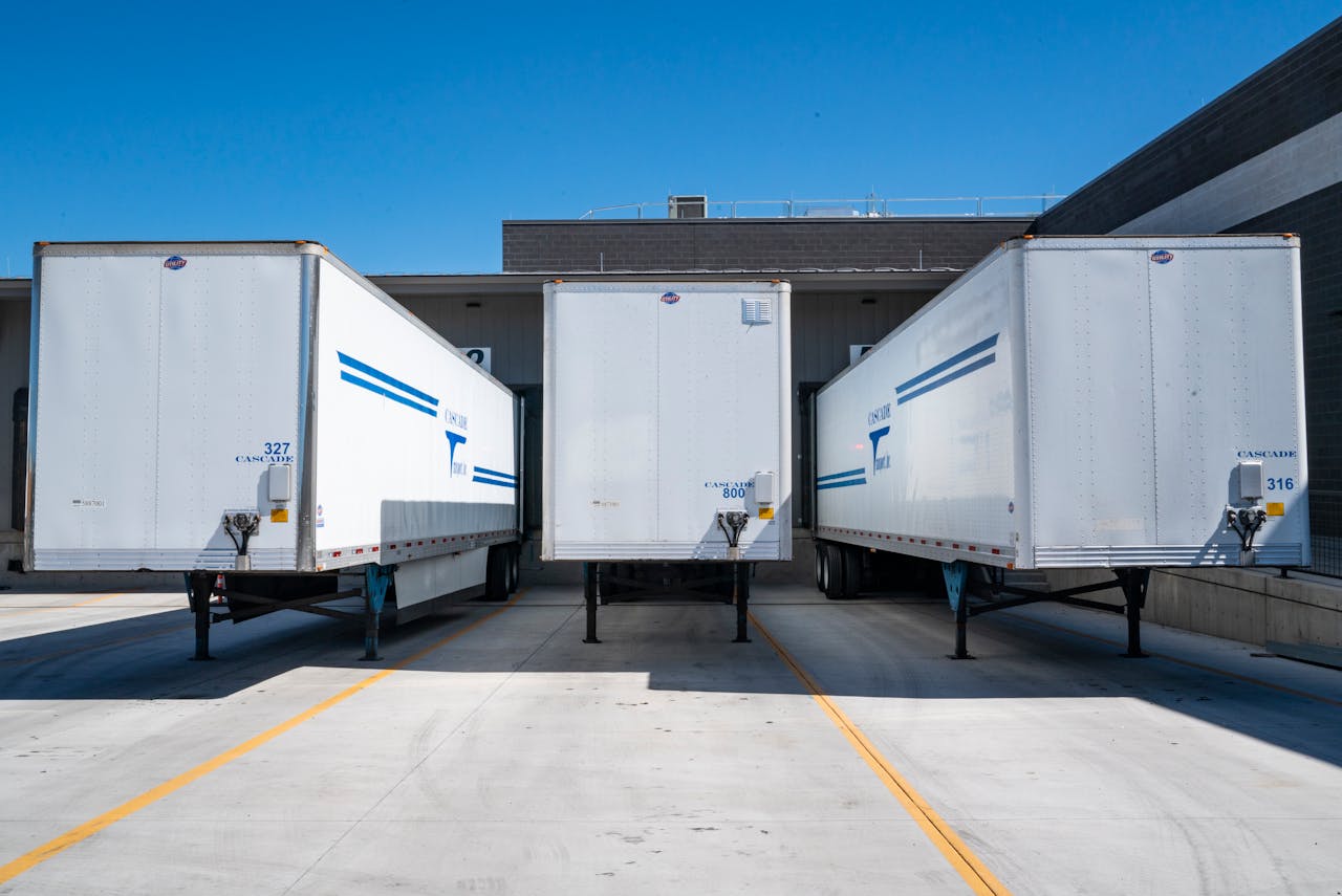 The Art of Drawing Readers In: Your attractive post title goes here Three white cargo trailers parked at an industrial shipping dock under clear blue skies.